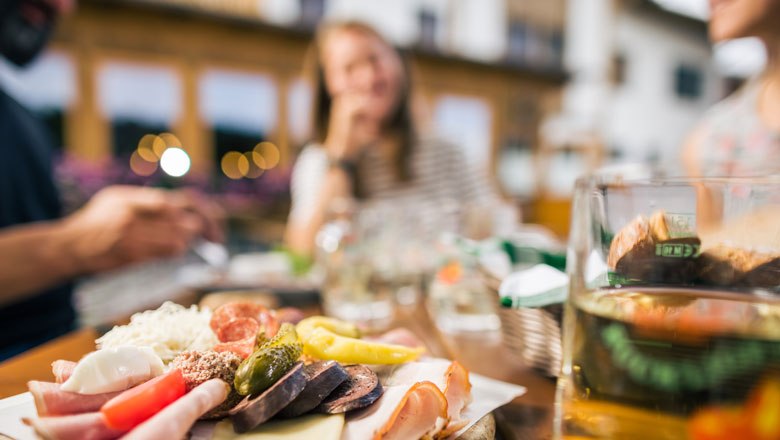 Ein Bild von einer Jause mit Fleisch, Käse, Brot, Gemüse und Most